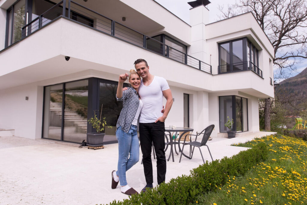 Casal em frente à casa própria conquistada com consórcio de imóvel