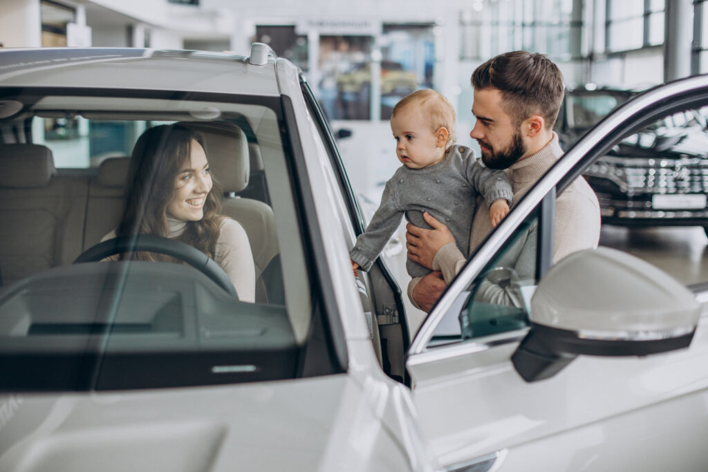 Família recebendo carro novo em concessionária com consórcio de veículo